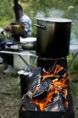a steaming pot cooking over a camp fire