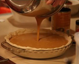 pouring the filling into the homemade pumpkin pie