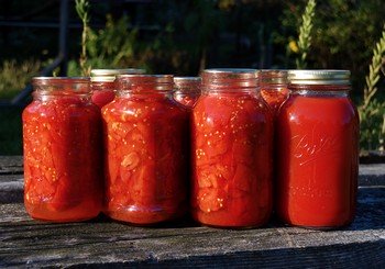 7 jars of canned tomatoes on a wooden table