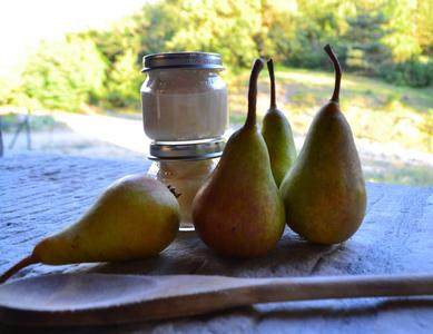 2 jars of homemade baby with pears and a wooden spoon.