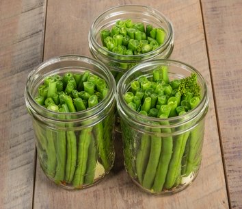 3 jars of canned beans on a wooden table.