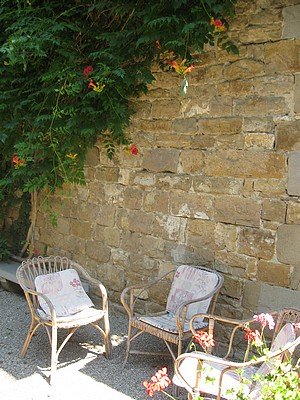 3 chairs in a country garden alongside a stone wall