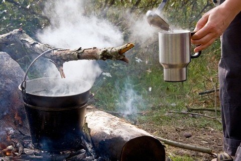 pouring water from a campfire bucket for tea