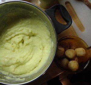 A pot of mashed potato with potatoes on the side