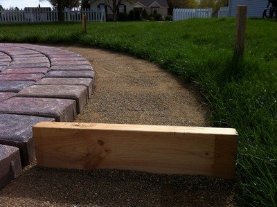 Knocking patio pavers into position with some wood.