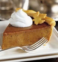 A wedge of pumpkin pie topped with cream.
