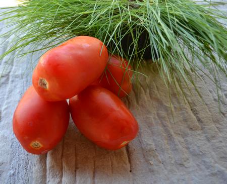 4 ripe San Marzano tomatoes on a stone table