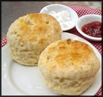 2 scones on a plate with cream and jam