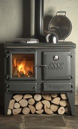 a black Esse woodstove with chopped wood on the floor